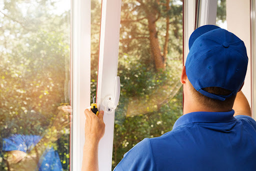 A Man wearing a blue shirt and blue hat installing a tilt and turn window